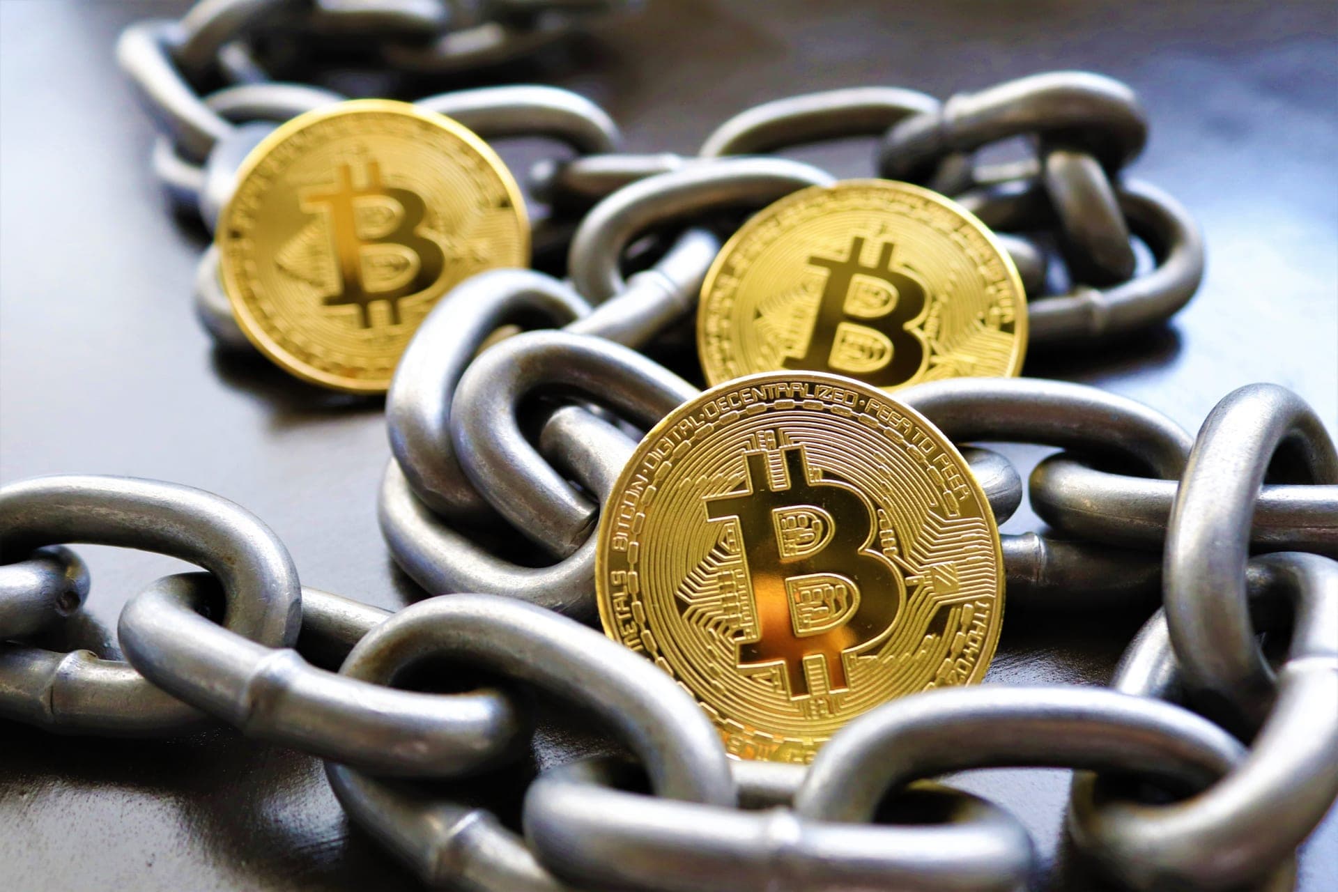 Gold Bitcoin coins resting on heavy steel chains
