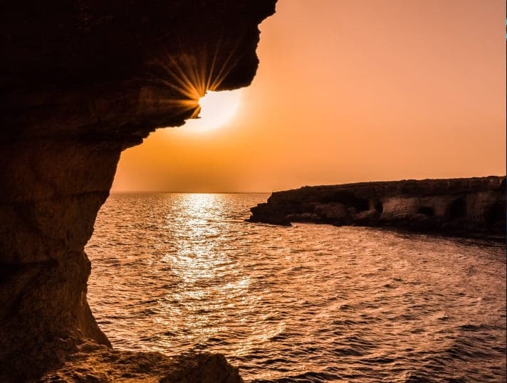 Sunset over the sea, seen from inside a rocky sea cave