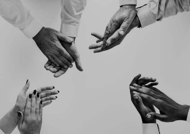 Black-and-white photograph of four pairs of hands applauding