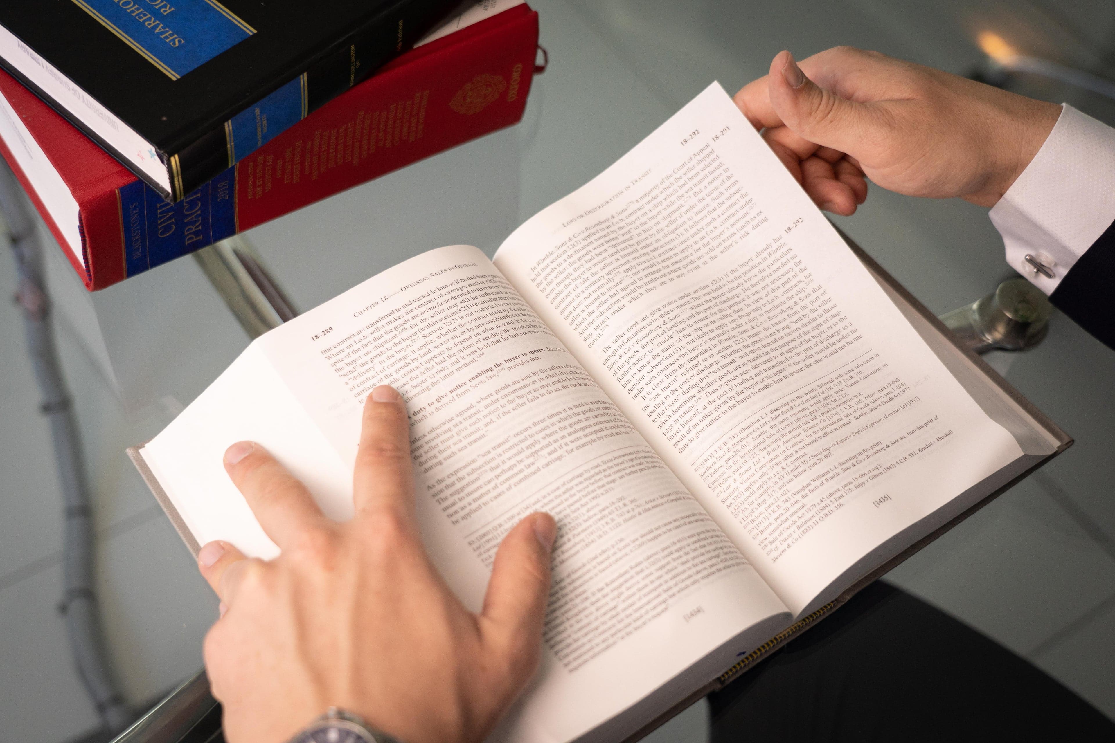 Reading an open law book at a glass desk